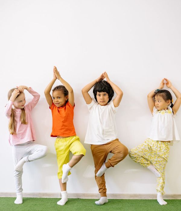 A child balancing in a tree yoga pose in a bright room.