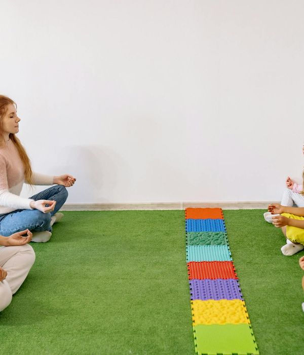 Group of kids sitting in a circle and smiling during a yoga class.